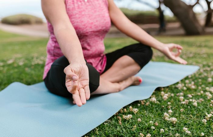 Close-up of a woman's hands in a yoga mudra, blurred background.